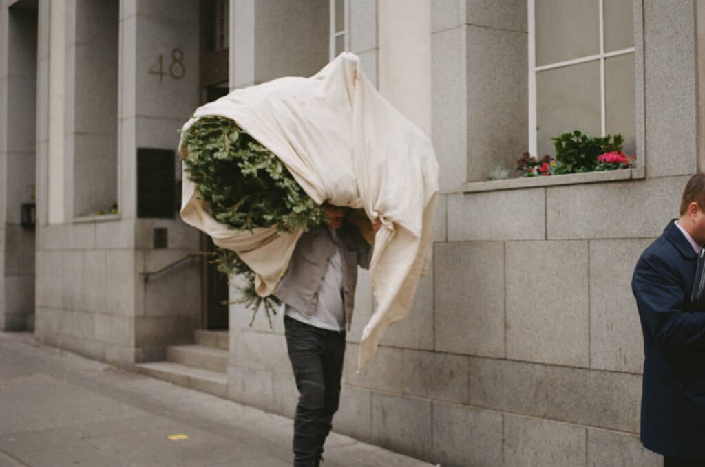 street photography picture of a man carrying a christmas tree in london
